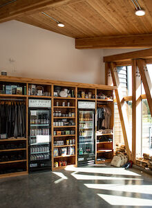 A cozy store interior with wooden shelves stocked with various products, natural light streaming through large windows.