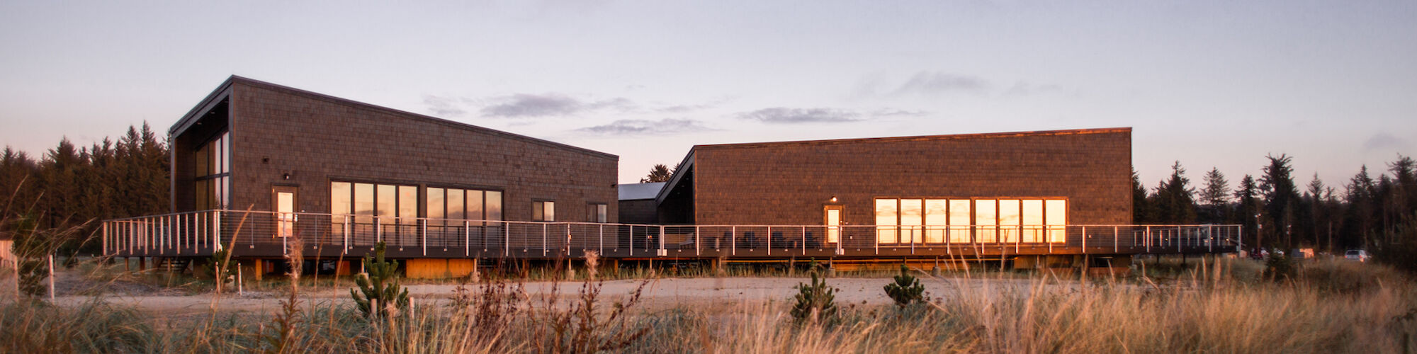 A modern building with large windows set amid grassy fields under an evening sky, capturing a peaceful and serene landscape.