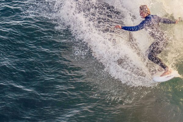 A surfer in a wetsuit rides a wave, carving through the ocean water with skill and speed.