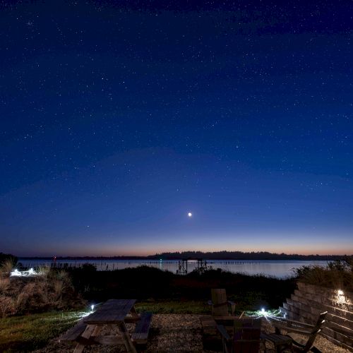 A starry night sky above a calm landscape, with a bright celestial object near the horizon and subtle foreground lighting.