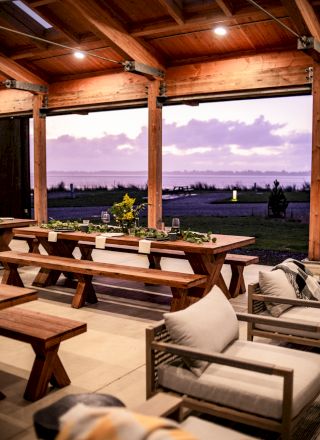 A cozy wooden patio with comfortable seating, a large dining table, and a view of an outdoor landscape at sunset.